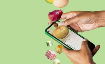 Närbild på händer som håller en smartphone med WWF:s app öppen, omgiven av svävande livsmedel som potatis, rödlök, ägg och avokado mot ljusgrön bakgrund. Bilden representerar digitala verktyg för klimatsmart matval.