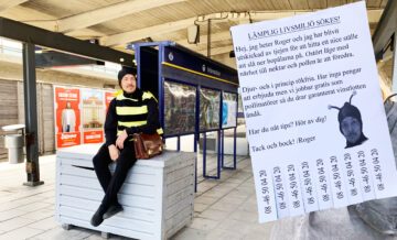 En man utklädd till ett bi som heter Roger sitter på på tunnelbaneperrongen och blickar ut. Till höger i bild syns ett papper som är skrivet som en kontaktannons med en bild på biet Rogers ansikte. På pappret står det: LÄMPLIG LIVSMILJÖ SÖKES! Hej, jag heter Roger och jag har blivit utskickad av tjejen för att hitta ett nice ställe att slå ner bopålarna på. Ostört läge med närhet till nektar och pollen är att föredra. Djur- och i princip rökfria. Har inga pengar att erbjuda men vi jobbar gratis som pollinatörer så du drar garanterat vinstlotten ändå. Har du nåt tips? Hör av dig! Tack och bock! /Roger