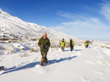 Fyra personer går i snön i bergen.