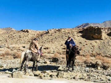 Två personer på häst i bergen.