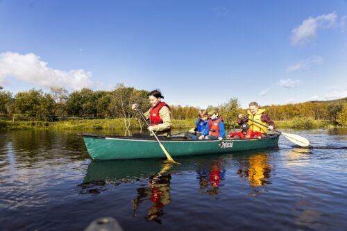 En familj paddlar på älven och letar skärp.