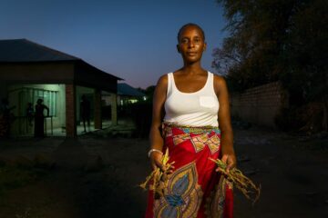Lucy Mbuzi displays the remnants of her vegetable garden outside