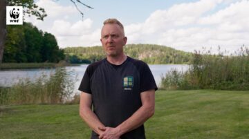 Årets Östersjöbonde 2025, Henrik Johnsson står mot kamera på en grön gräsmatta framför vatten.