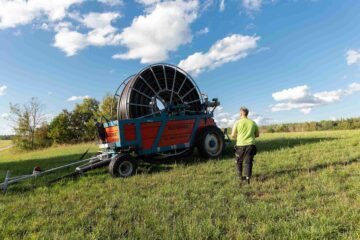 Årets Östersjöbonde 2025, Gabriel Jonsson går bort genom gräset mot en stor kabelvinda på släp. Ogestad Egendom och Hyllela gård, Västerviks kommun, Småland, Sverige