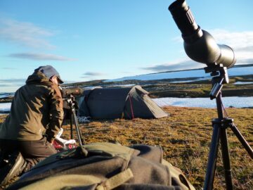 Person hukar, i bakgrunden syns tält och kamerautrustning.