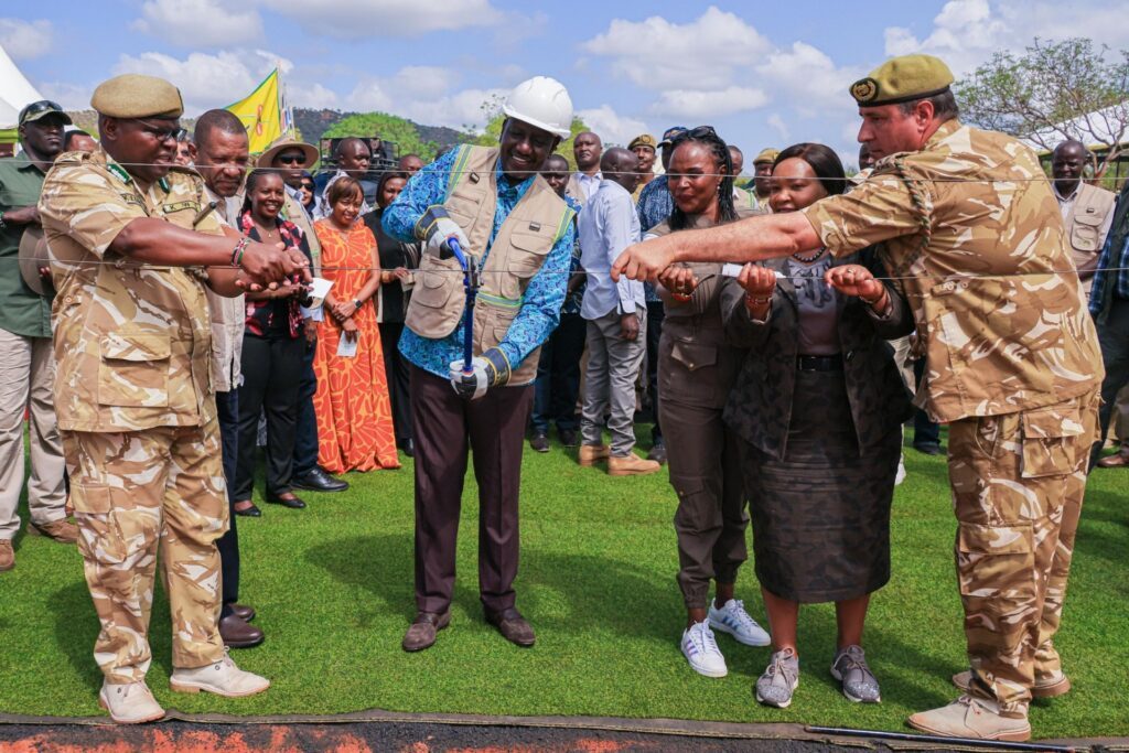 President William Ruto (i mitten med vit hjälm) Klipper ett staket i Tsavo West nationalpark. Andra personen till höger är, Hon. Rebecca Miano. Till höger är kabinettsekreterare för turism och natur- och djurliv, Silvia Museiya. Tredje till vänster står statssekreteraren för departementet för natur- och djurliv. Till vänster Kenya Wildlife Service generaldirektör Dr. Erustus Kanga. Till vänster Michael Nicholson, KWS ansvarig för natur- och djurliv och samhällstjänster.