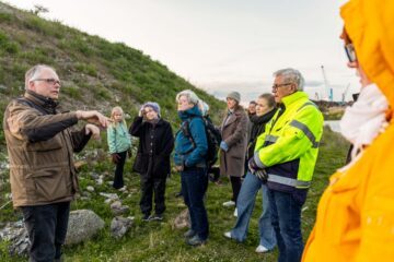 Biologen Mats Wirén syns till vänster i bilden, vänd mot en grupp människor till höger i bilden, och tycks berättar något för gruppen.