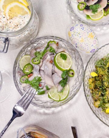 Ett fat med sill filer blandat med lime, koriander, jalapeno och kryddpeppar. Sillen ligger i ett fat på ett bord.