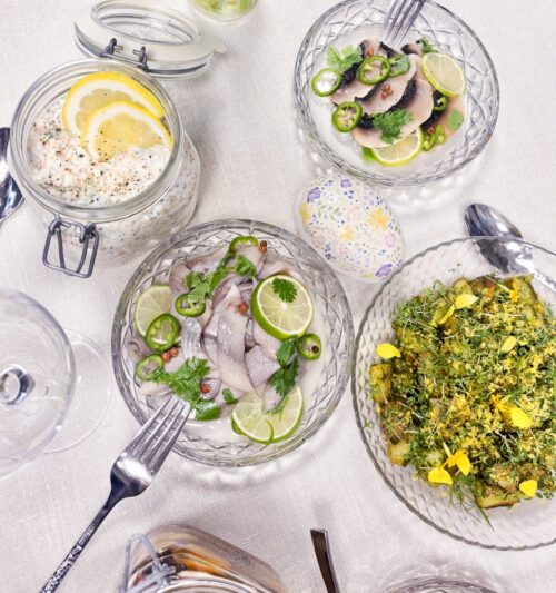 Bilder på ett påskbord med tre burkar med sill och örtslungad potatis med gravad äggula.