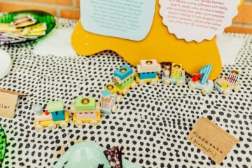 Leksakståg i trä syns mot en prickig matta.