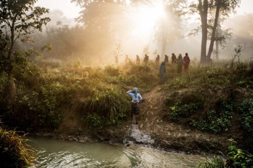 Women cross a river on their way to work in Bardia, Nepal.