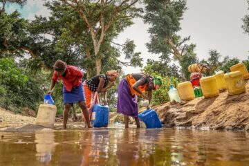 Kvinnor stor i ett vattendrag för att hämta vatten i Loita, Kenya.